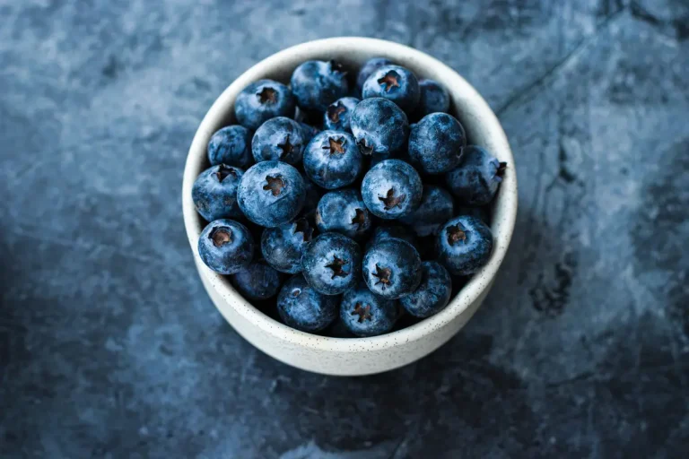 Kasede taze blueberry meyveleri ve yeşil yapraklar